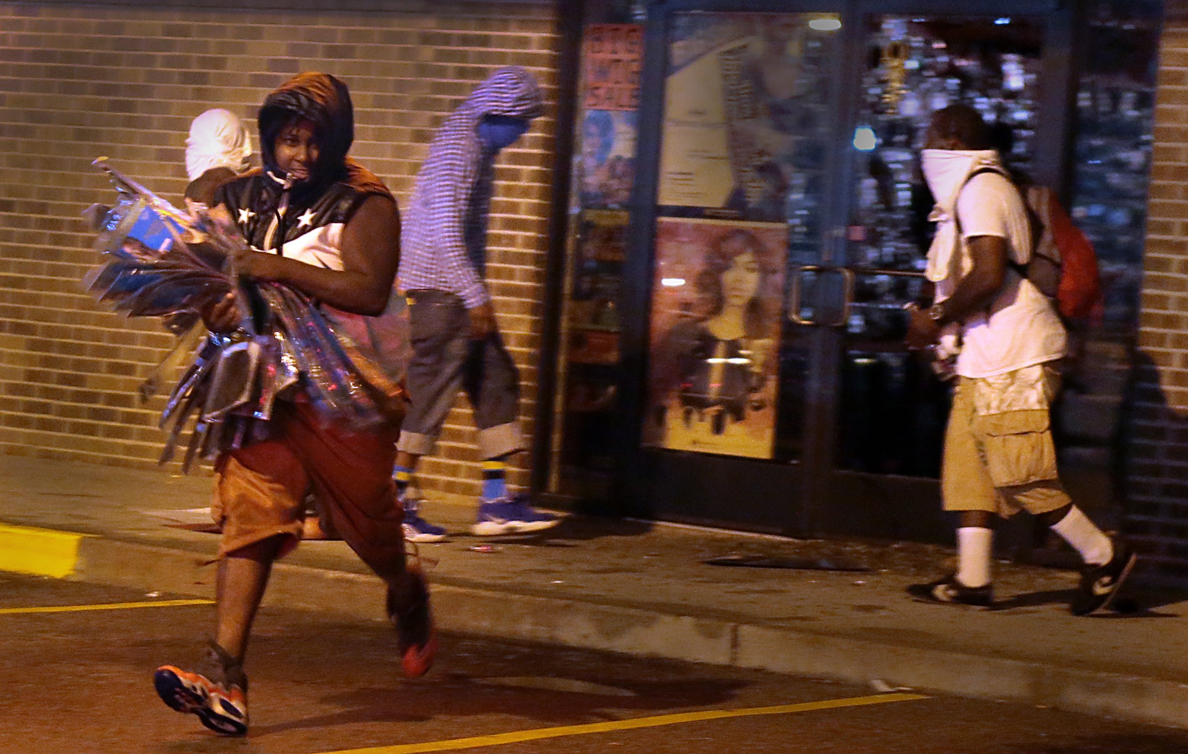 PHOTO: A looter escapes with items from Feel Beauty Supply on West Florissant Avenue in Ferguson early Saturday, Aug. 16, 2014, after protestors clashed with police.