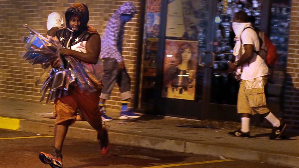 PHOTO: A looter escapes with items from Feel Beauty Supply on West Florissant Avenue in Ferguson early Saturday, Aug. 16, 2014, after protestors clashed with police.