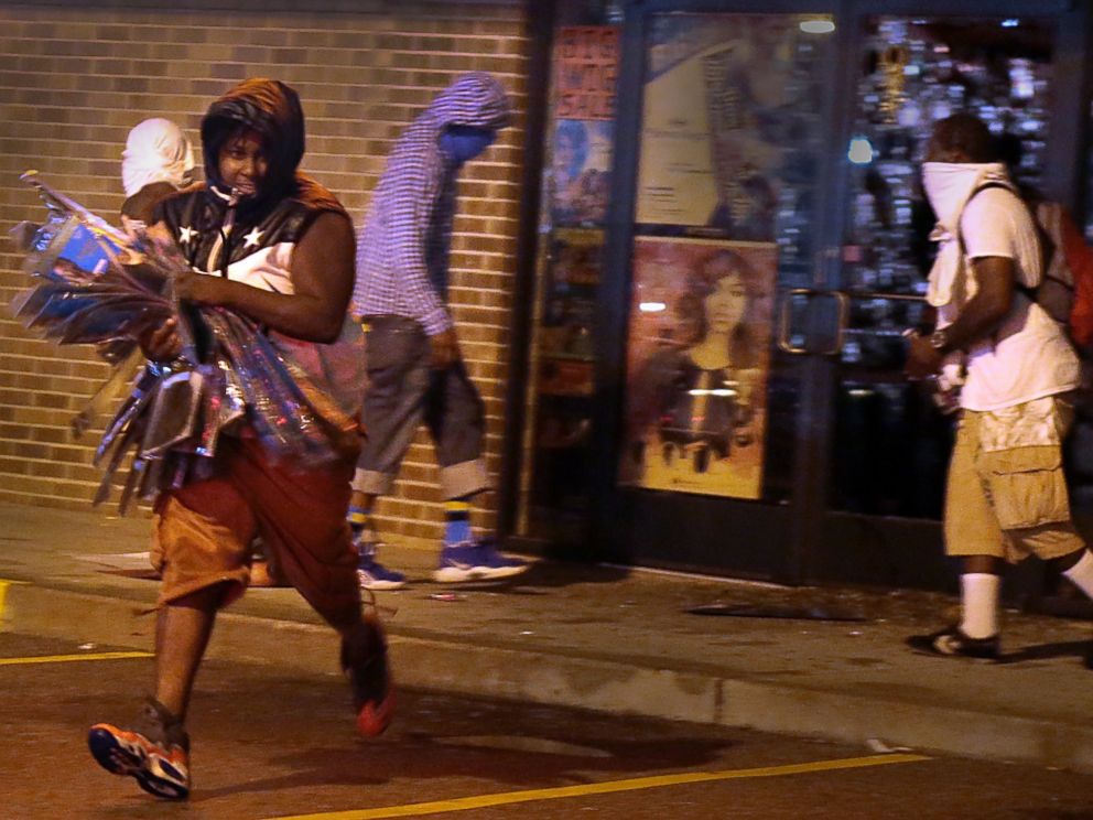 PHOTO: A looter escapes with items from Feel Beauty Supply on West Florissant Avenue in Ferguson early Saturday, Aug. 16, 2014, after protestors clashed with police.