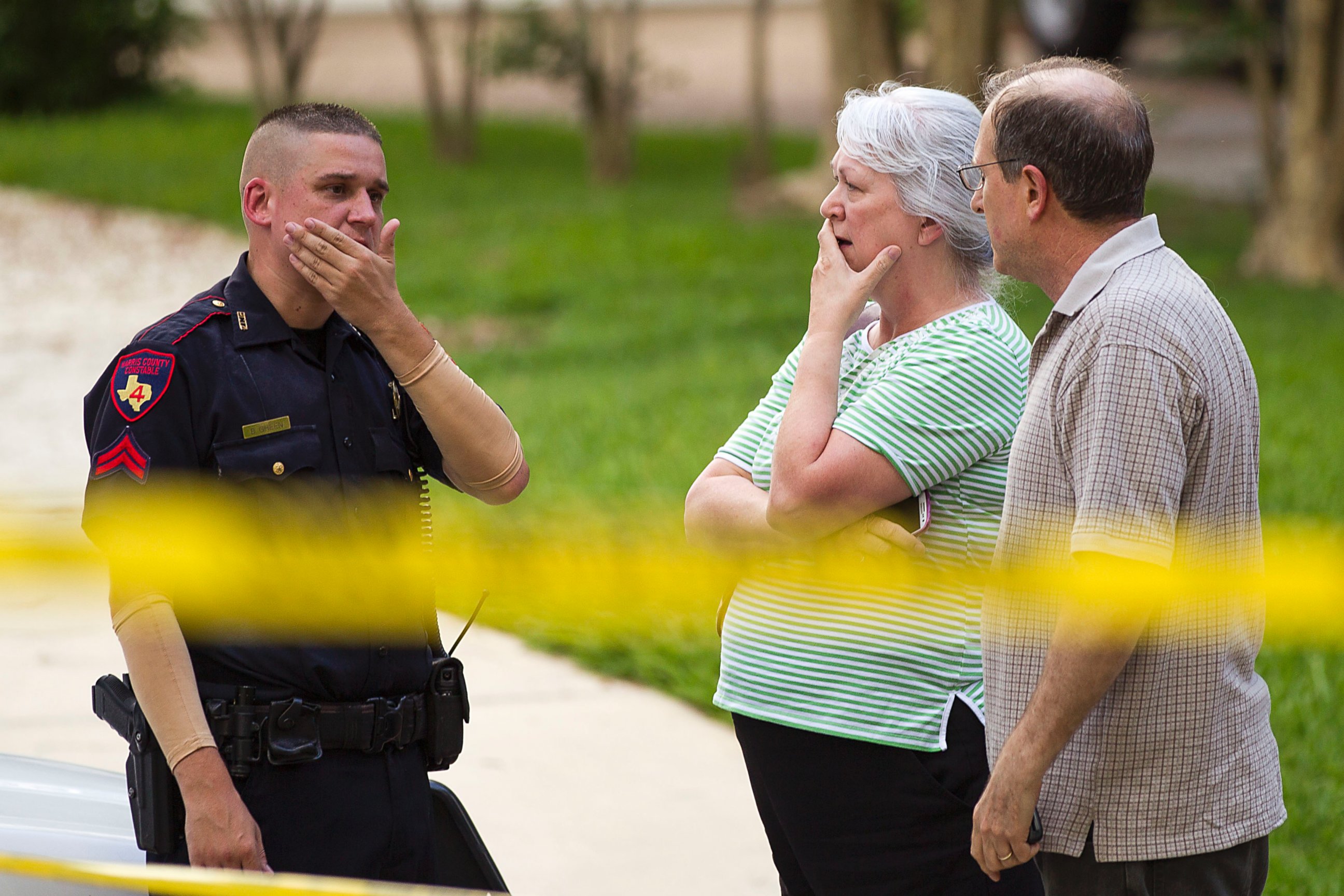 PHOTO:  People stand with a law enforcement officer near the scene of a shooting, July 9, 2014, in Spring, Texas.