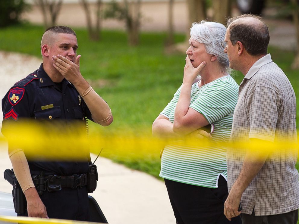 PHOTO: People stand with a law enforcement officer near the scene of a shooting, July 9, 2014, in Spring, Texas.