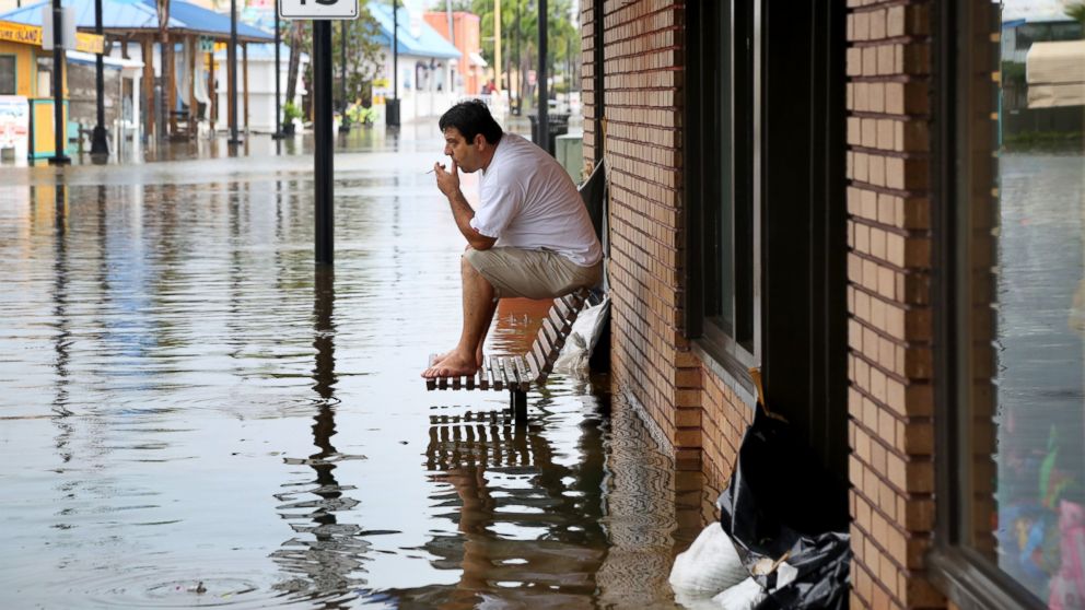 PHOTO: Pedro Muacaj rests on higher ground in front of a gift shop along a flooded section of  Dodecanese Blvd. in Tarpon Springs, Fla. where he was working, Sept. 1, 2016. 