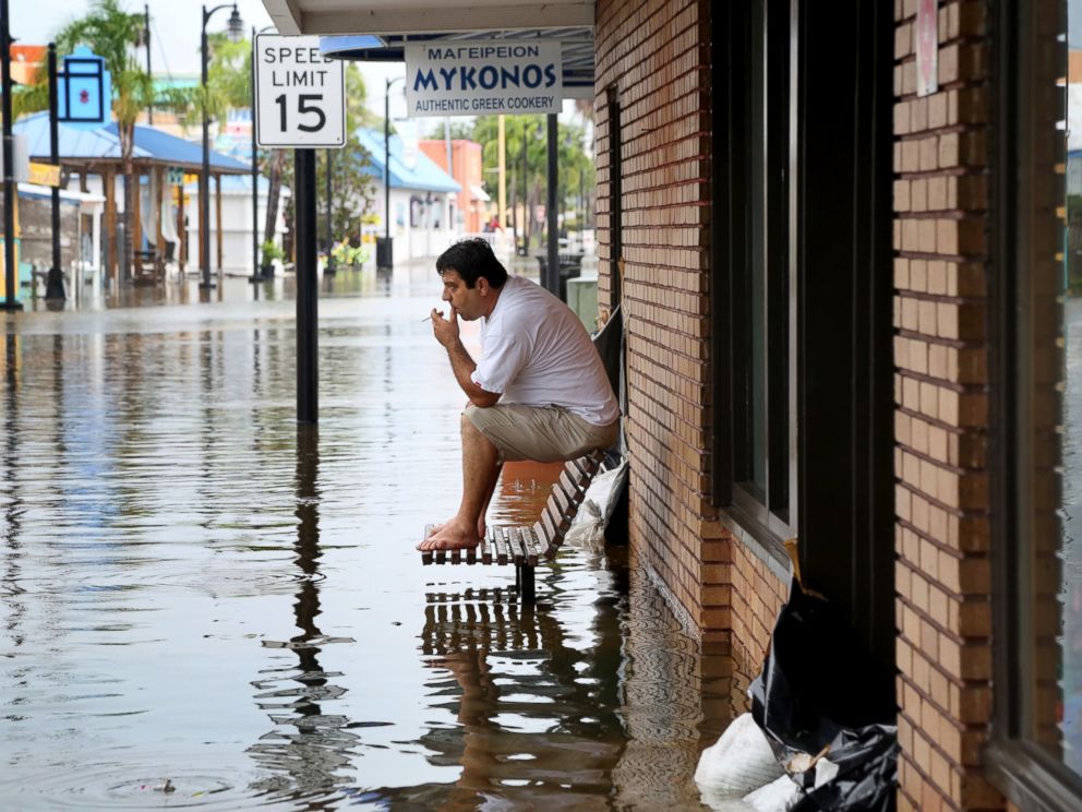 PHOTO: Pedro Muacaj rests on higher ground in front of a gift shop along a flooded section of Dodecanese Blvd. in Tarpon Springs, Fla. where he was working, Sept. 1, 2016.
