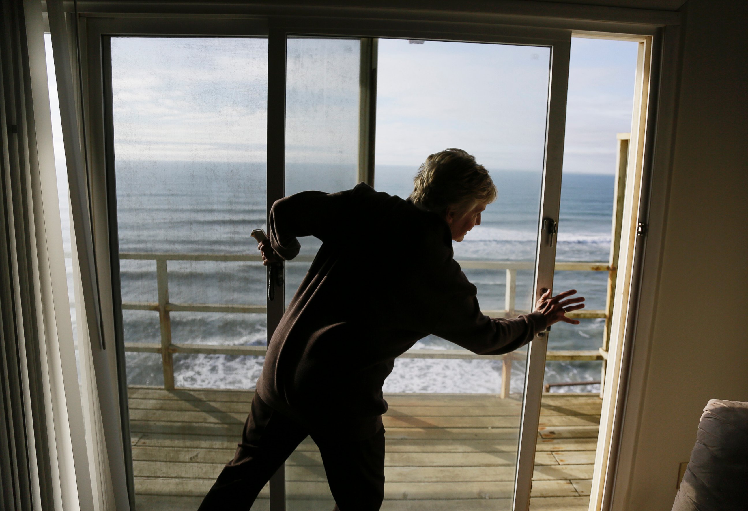 PHOTO: Eileen Horan shuts the door to her patio overlooking the Pacific Ocean after being forced to evacuate her apartment on Jan. 25, 2016, in Pacifica, Calif. 