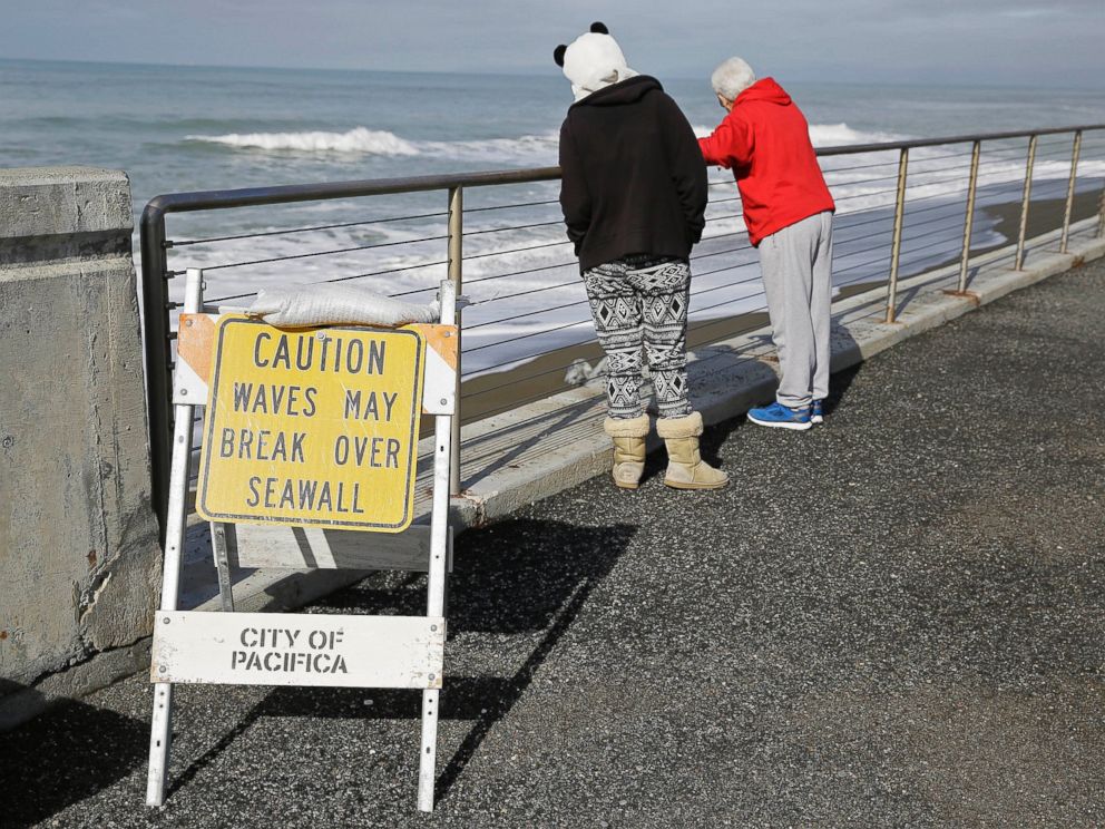 PHOTO: A couple looks at waves breaking near the seawall, Jan. 25, 2016, in Pacifica, Calif. Strong waves caused by El Nino storms ate away part of the sea wall in the coastal community, threatening homes and an apartment building.