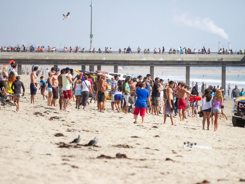 PHOTO: Pedestrians at Venice Beach, Calif. watch as lifeguards bring in a swimmer rescued from the water after a lightning strike, July 27, 2014.