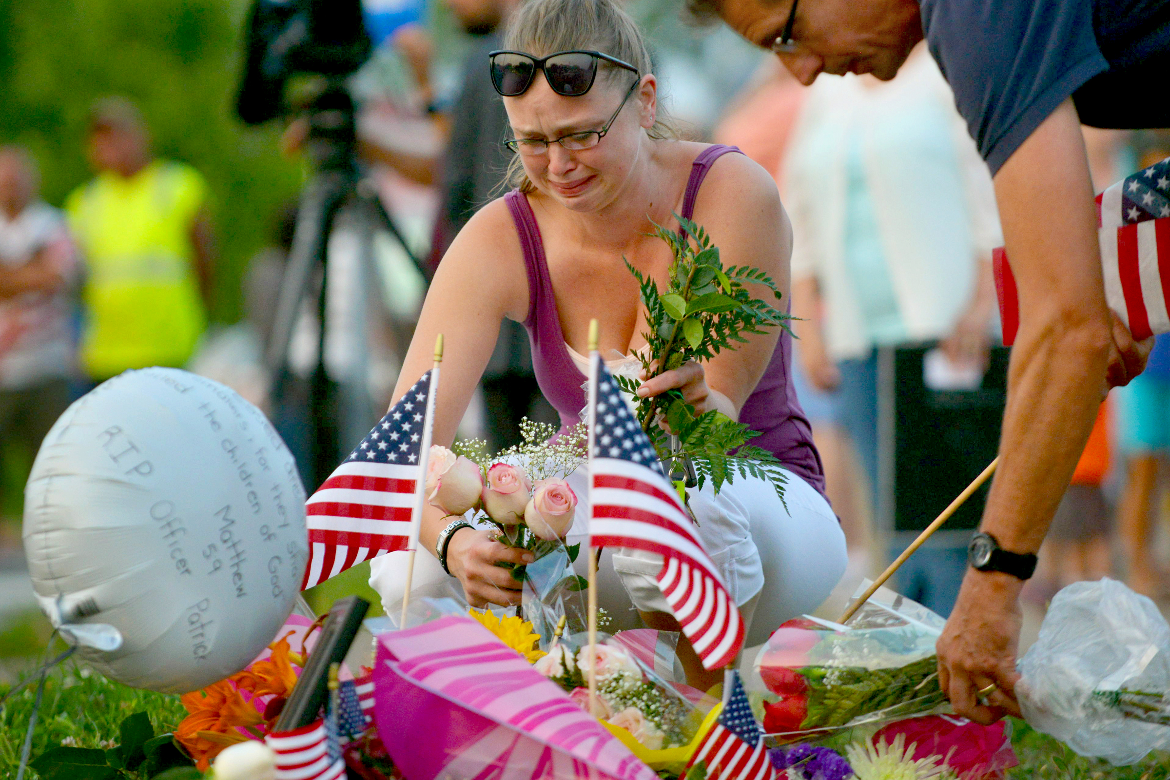 PHOTO: Gail Krull of West St. Paul, Minn. cries as she lays a bouquet of roses on a makeshift memorial following a fatal shooting in West St. Paul, Minn., July 30, 2014.