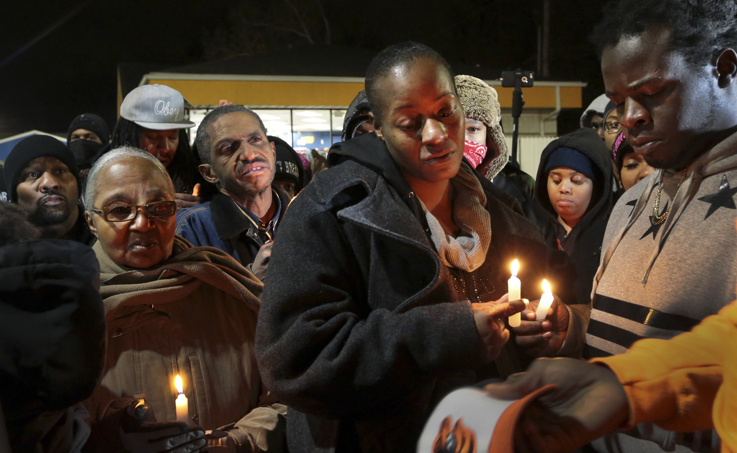 PHOTO: Toni Martin-Green, front center, and her husband Jerome Green, right, participate in a candlelight vigil at a Berkeley, Mo., gas station on Dec. 24, 2014.