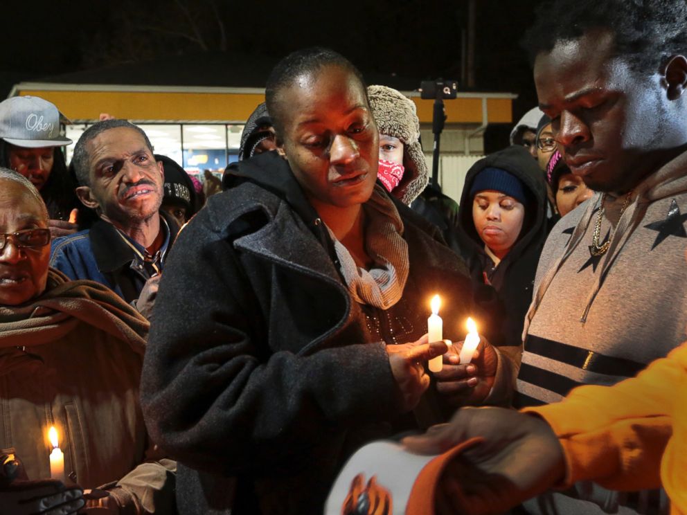 PHOTO: Toni Martin-Green, front center, and her husband Jerome Green, right, participate in a candlelight vigil at a Berkeley, Mo., gas station on Dec. 24, 2014.
