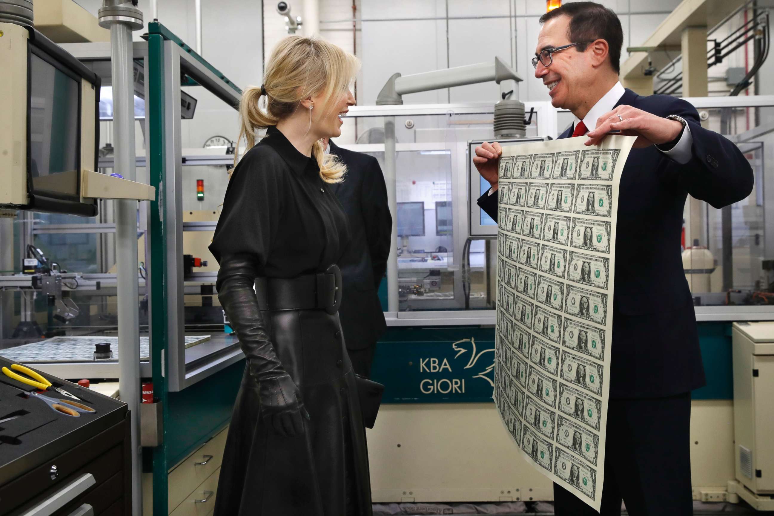 Treasury Secretary Steven Mnuchin, right, and his wife Louise Linton, left, react as Mnuchin holds up a sheet of new $1 bills, the first currency notes bearing his and U.S. Treasurer Jovita Carranza's signatures, Wednesday, Nov. 15, 2017.