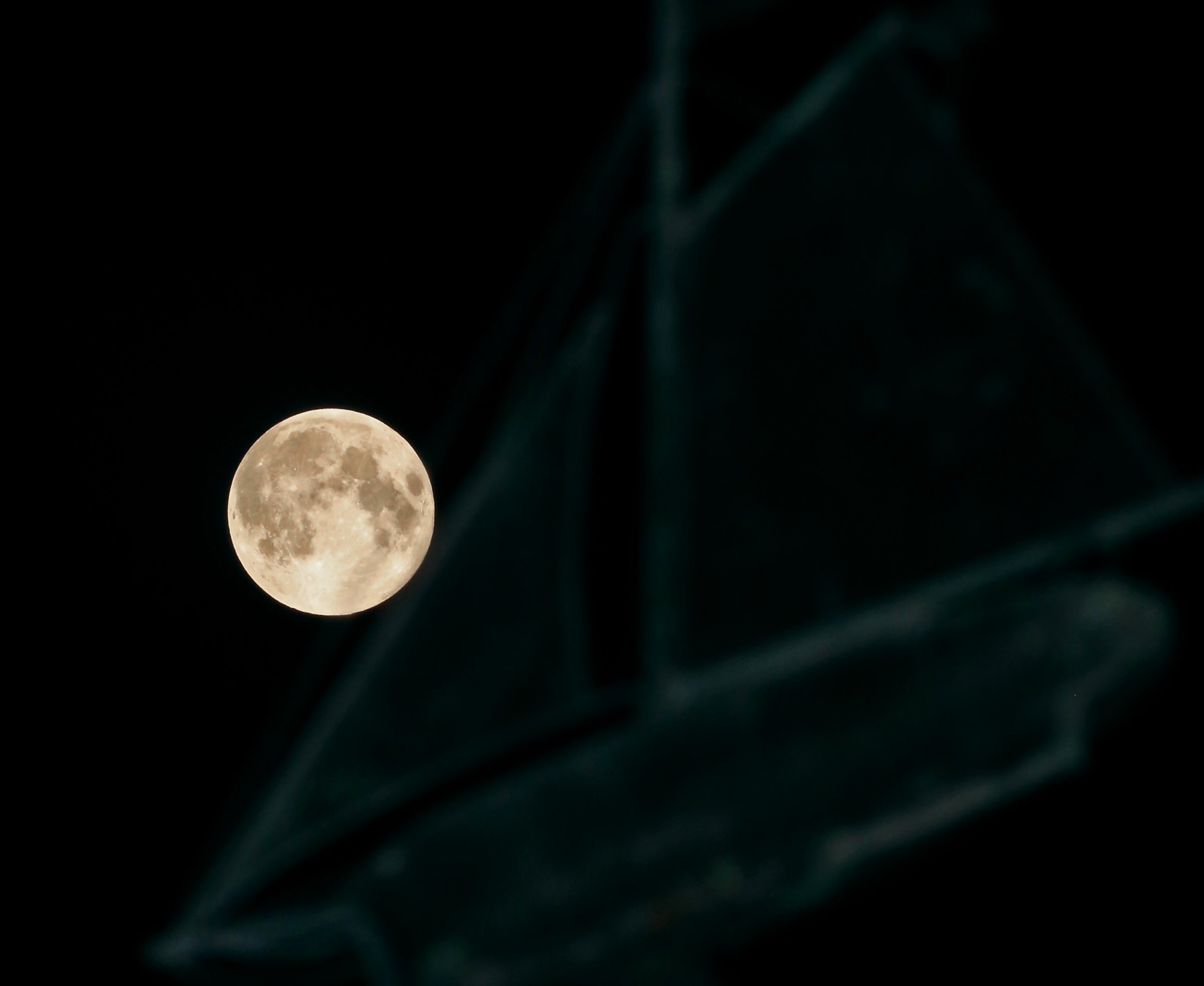 PHOTO: A full moon ascends behind a sailboat-themed weather vane in the city of Oconomowoc, Wis., Sept. 8, 2014.