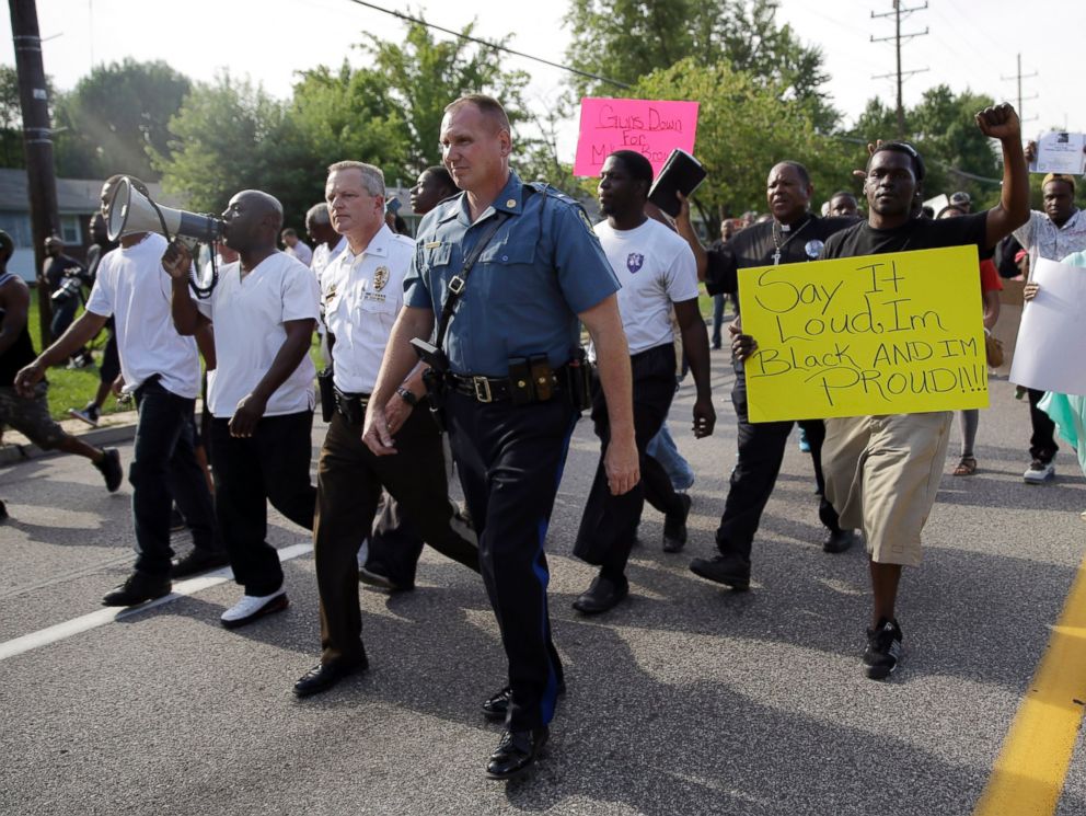 PHOTO: Thousands of demonstrators peacefully march down a street with members of the St. Louis County Police and Missouri Highway Patrol Thursday, Aug. 14, 2014, in Ferguson, Mo.