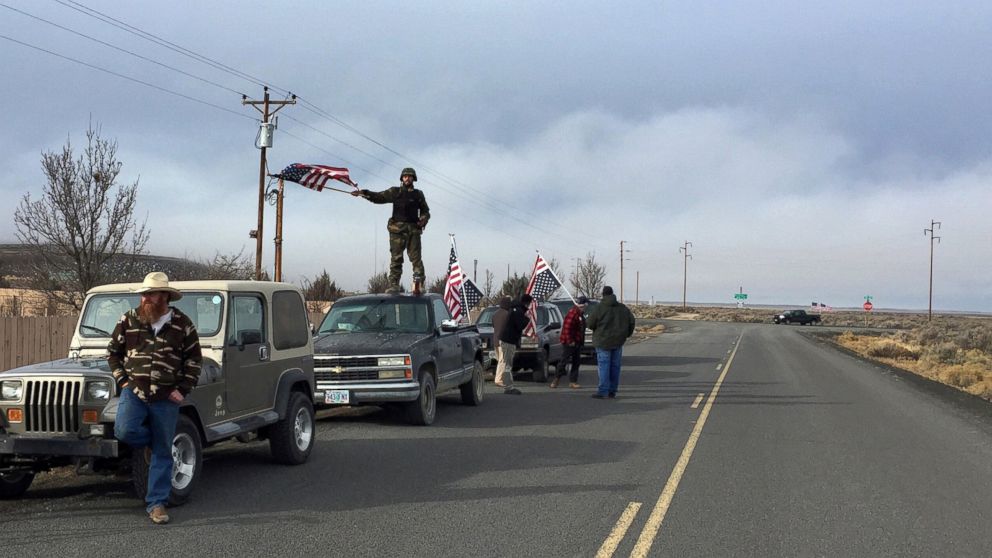 People wave American flags near the Malheur National Wildlife Refuge, Feb. 11, 2016, near Burns, Ore. The last four armed occupiers of the national wildlife refuge in eastern Oregon said they would turn themselves in Thursday morning, after law officers surrounded them in a tense standoff. 