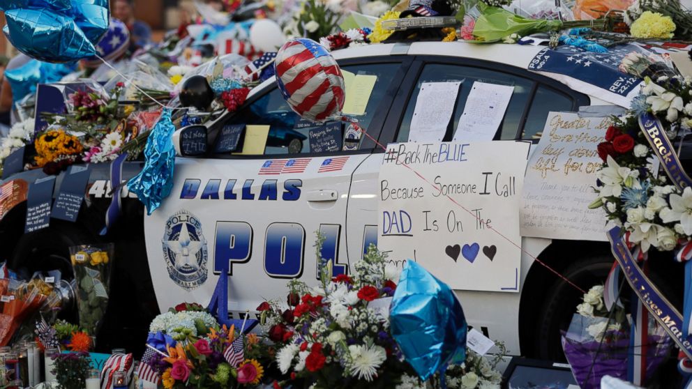 Notes, flowers and other items decorate a squad car at a memorial in front of the Dallas police department, July 9, 2016, in Dallas. Five police officers are dead and several injured following a shooting in downtown Dallas.