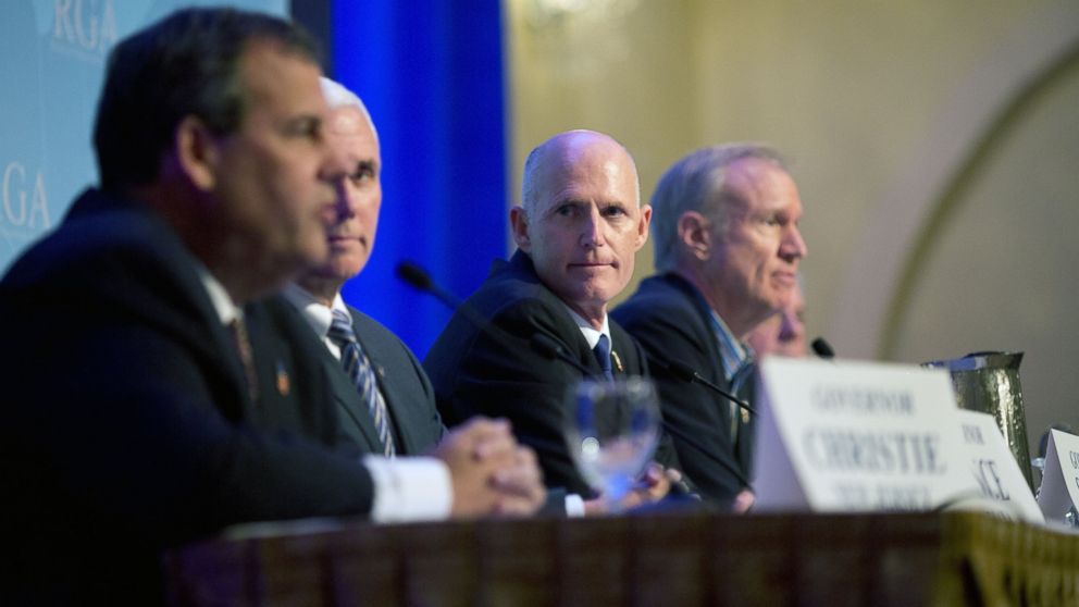 Florida Gov. Rick Scott, center, listens as New Jersey Gov. Chris Christie, left,  talks about immigration reform during a press conference at the Republican governors' conference in Boca Raton, Fla., Nov. 19, 2014.