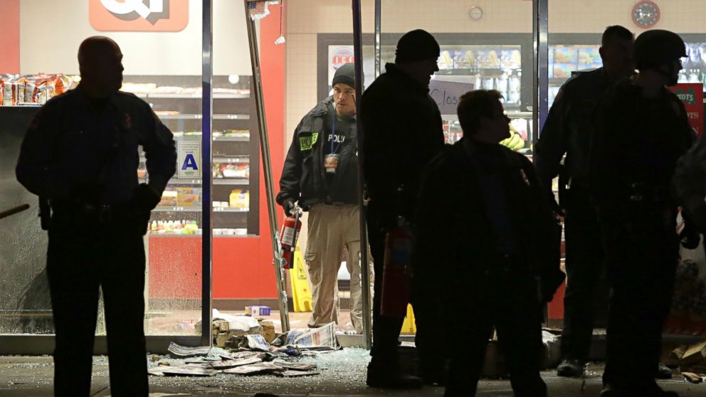 PHOTO: A police officer with a fire extinguisher stands in the broken out entry to a QuikTrip, Dec. 24, 2014, following a shooting nearby in Berkeley, Mo.