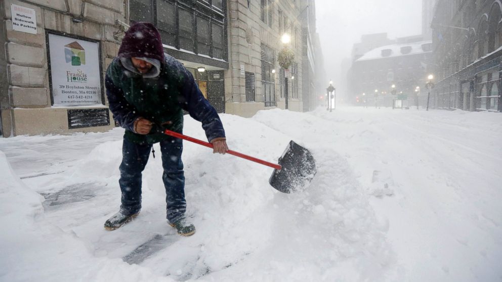 A worker shovels snow from a sidewalk during a winter snowstorm, Jan. 27, 2015, in Boston.