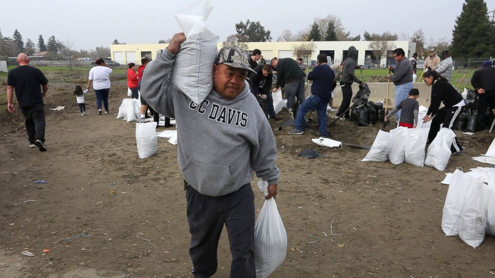 Sam Taing carries sandbags to his pickup truck to be placed around his home in the Sacramento suburb of North Highlands, Calif., Dec. 10, 2014.