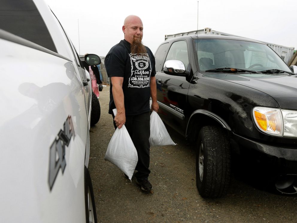 PHOTO: Carl Corbin carries sandbags to his vehicle to be placed around the home of an elderly couple he lives near in the Sacramento suburb of North Highlands, Calif., Dec. 10, 2014.