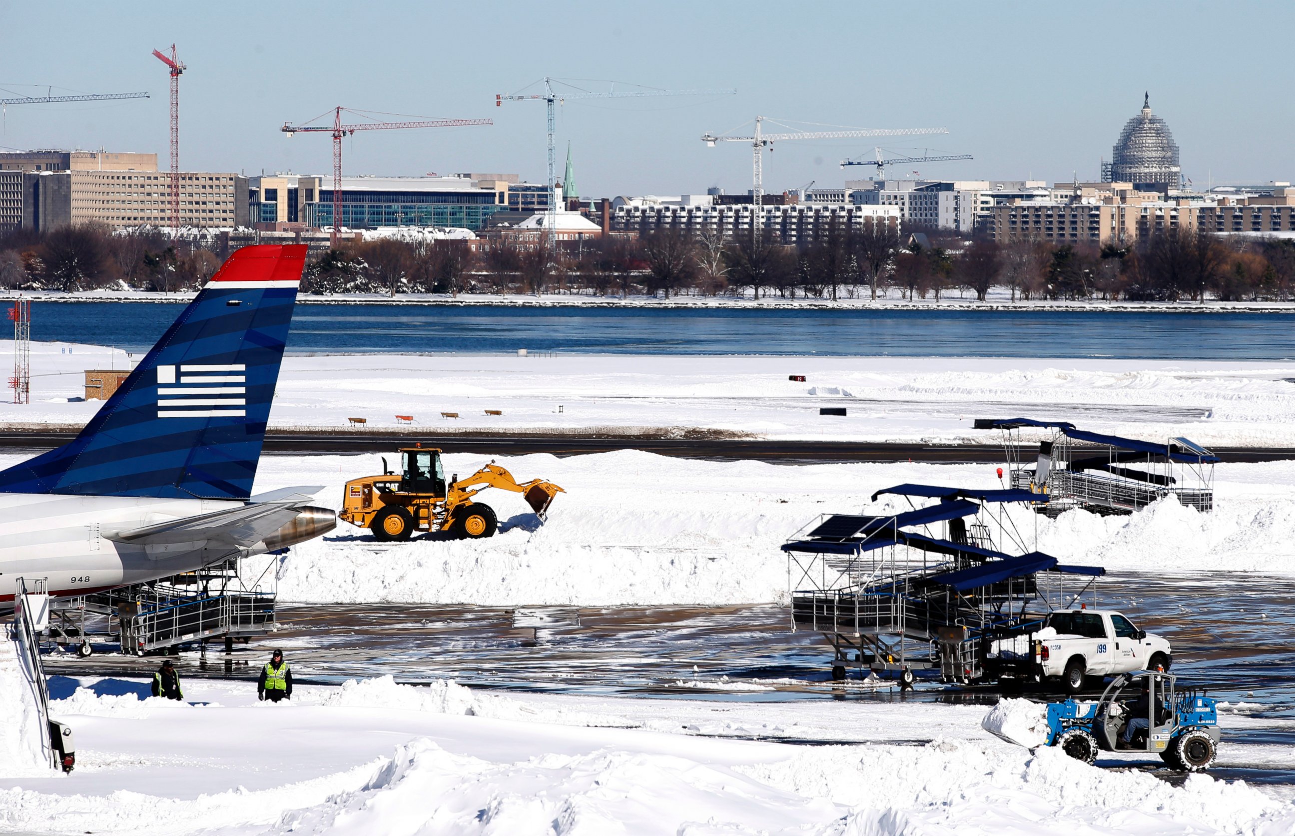 PHOTO:Workers clear snow on the tarmac at Ronald Reagan National Airport, with the U.S. Capitol dome in the background, Jan. 24, 2016 in Arlington, Va.