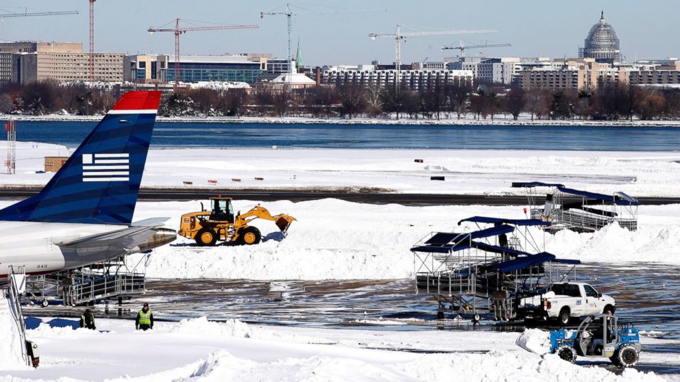 PHOTO:Workers clear snow on the tarmac at Ronald Reagan National Airport, with the U.S. Capitol dome in the background, Jan. 24, 2016 in Arlington, Va.