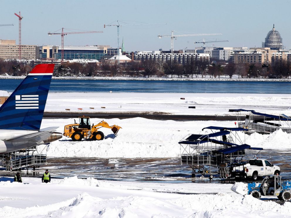 PHOTO:Workers clear snow on the tarmac at Ronald Reagan National Airport, with the U.S. Capitol dome in the background, Jan. 24, 2016 in Arlington, Va.