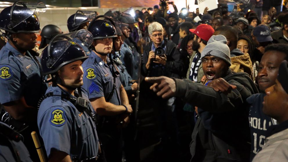 Protesters lock arms as they stand before a line of Missouri State Highway Patrol troopers in front of the Ferguson Police Department on Friday, Oct. 10, 2014. 