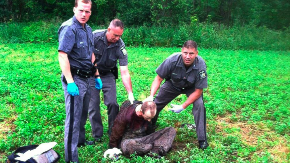 Police stand over David Sweat after he was shot and captured near the Canadian border Sunday, June 28, 2015, in Constable, N.Y. 