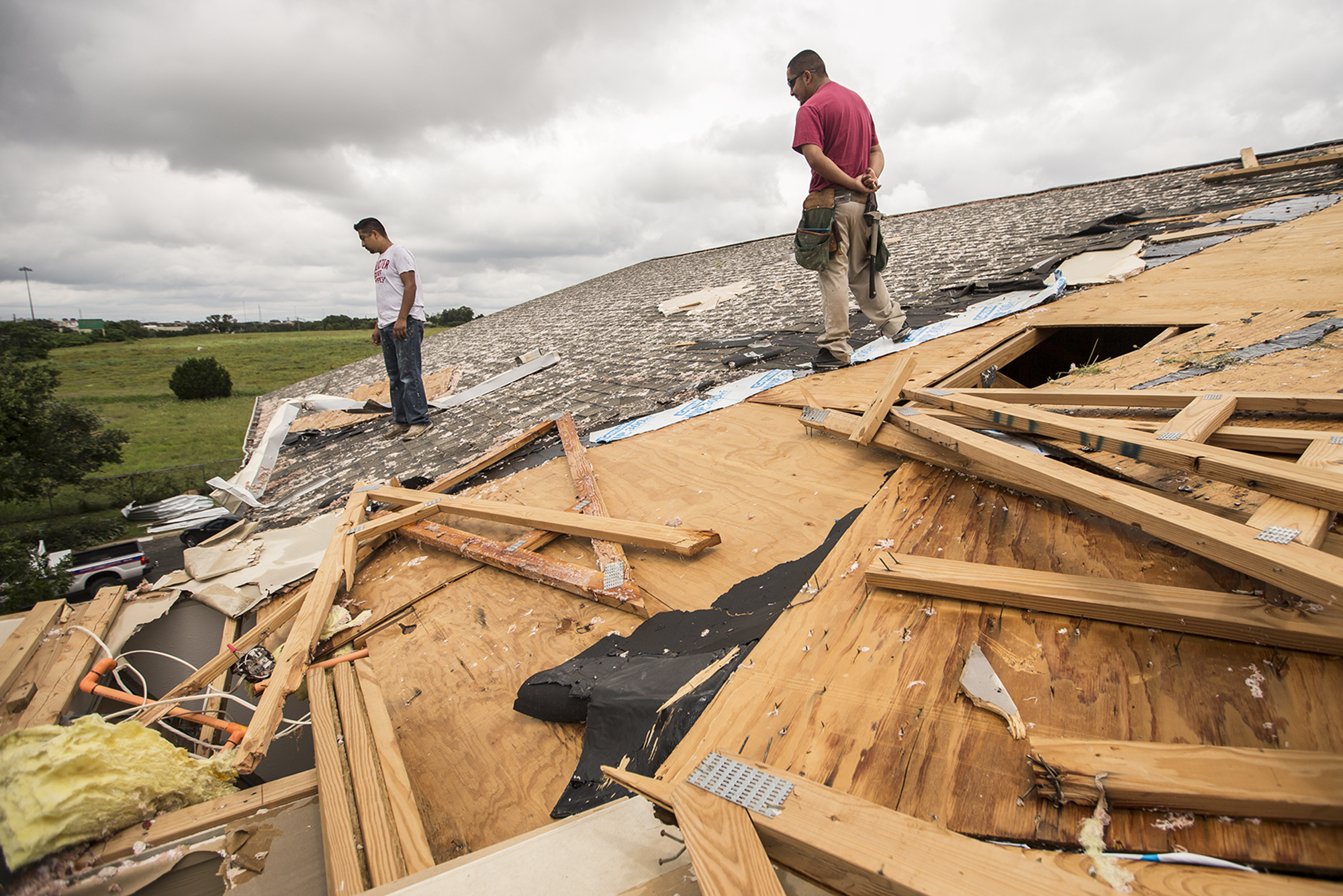 PHOTO: Edgar Mascorro, left, and Emir Nevarez check out the damage on the rooftop at the Silver Springs Apartments in North Austin, Texas, May 24, 2015.