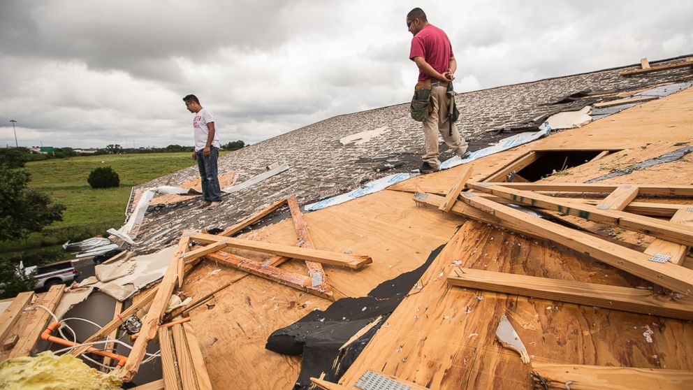 PHOTO: Edgar Mascorro, left, and Emir Nevarez check out the damage on the rooftop at the Silver Springs Apartments in North Austin, Texas, May 24, 2015.