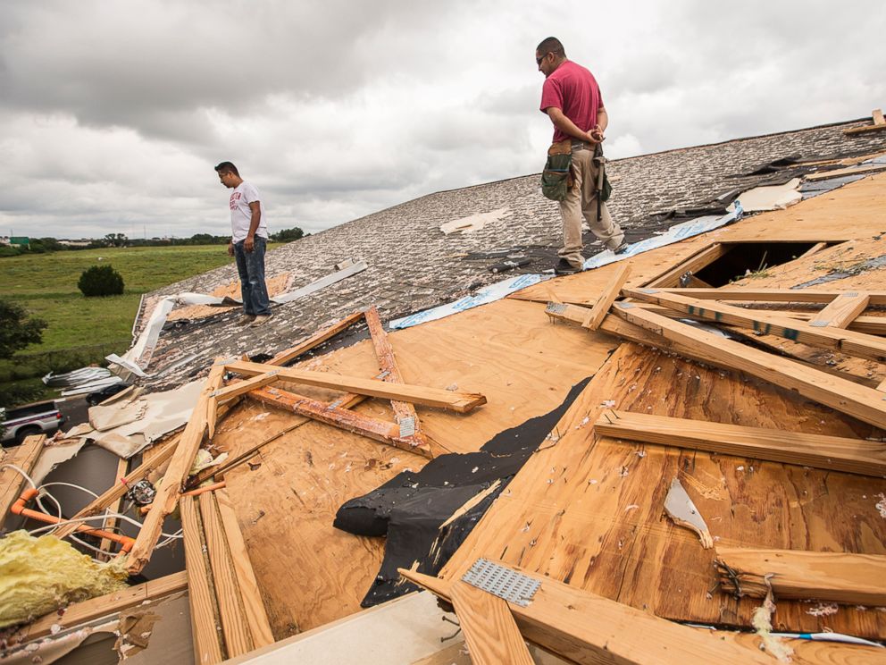 PHOTO: Edgar Mascorro, left, and Emir Nevarez check out the damage on the rooftop at the Silver Springs Apartments in North Austin, Texas, May 24, 2015.