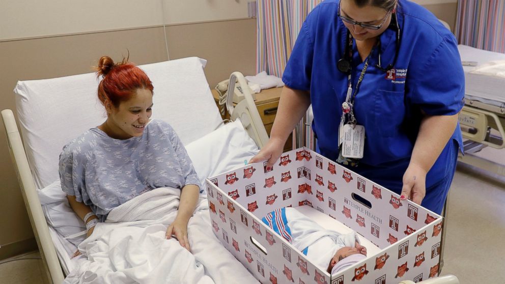 Keyshla Rivera smiles at her newborn son, Jesus, as registered nurse Christine Weick demonstrates a baby box before her discharge from Temple University Hospital in Philadelphia on May 6, 2016. In an effort to reduce infant mortality the boxes which are functioning bassinets complete with a sheet and mattress as well as essential baby supplies will be given free-of-charge to all mothers who deliver at the hospital.