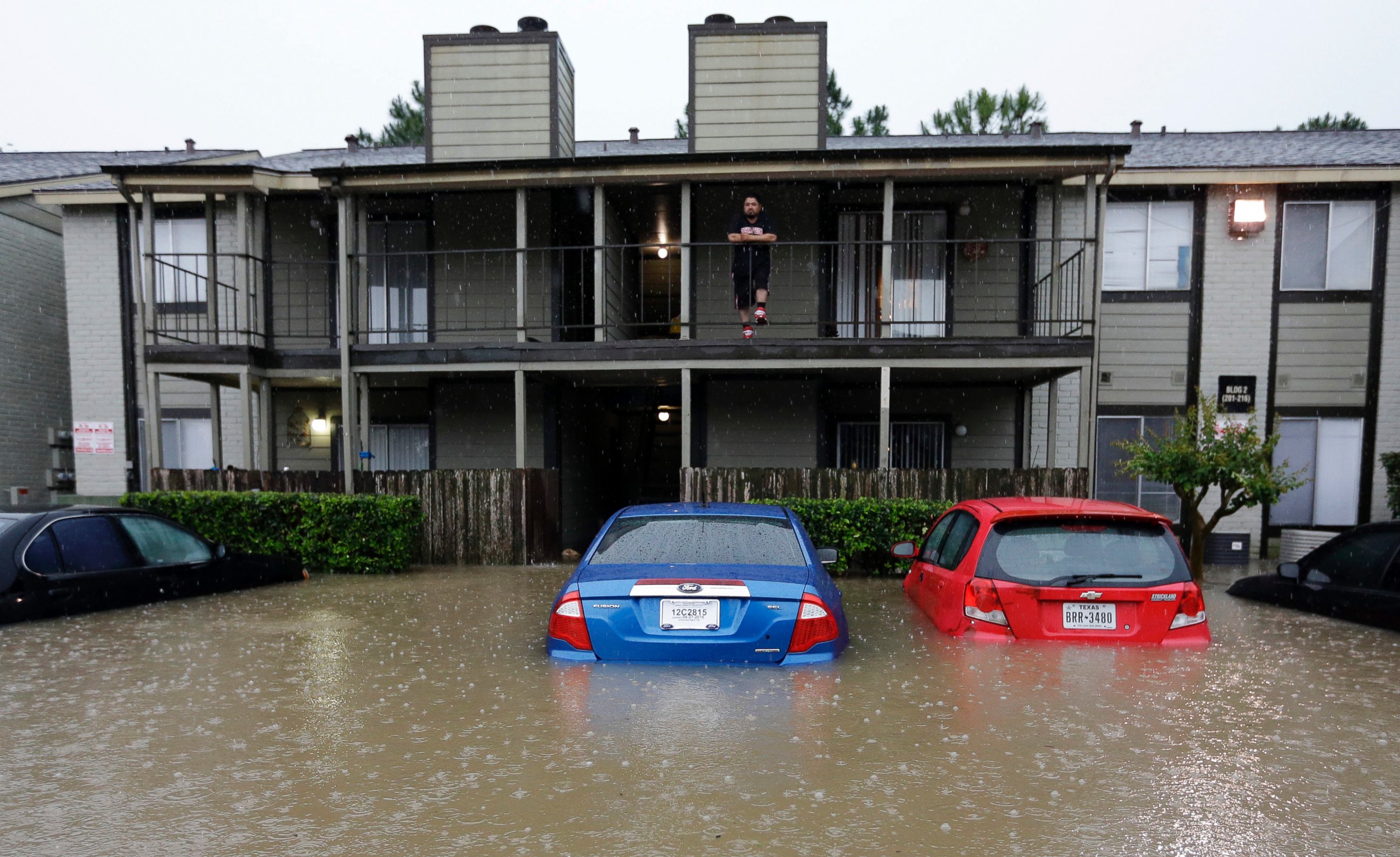 PHOTO: A resident looks out from the second floor as floodwaters surround his apartment complex on April 18, 2016, in Houston. 
