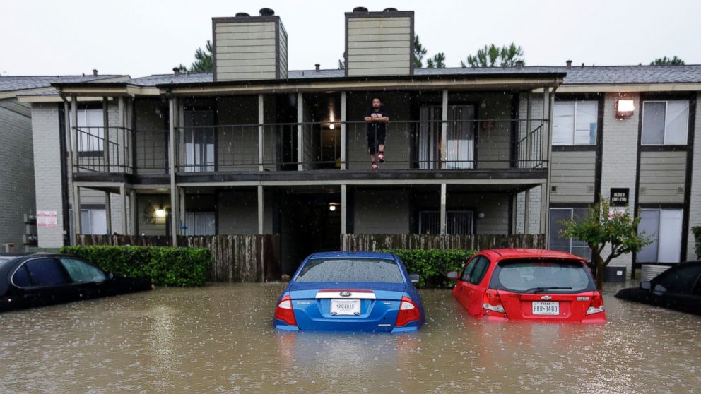 PHOTO: A resident looks out from the second floor as floodwaters surround his apartment complex on April 18, 2016, in Houston. 
