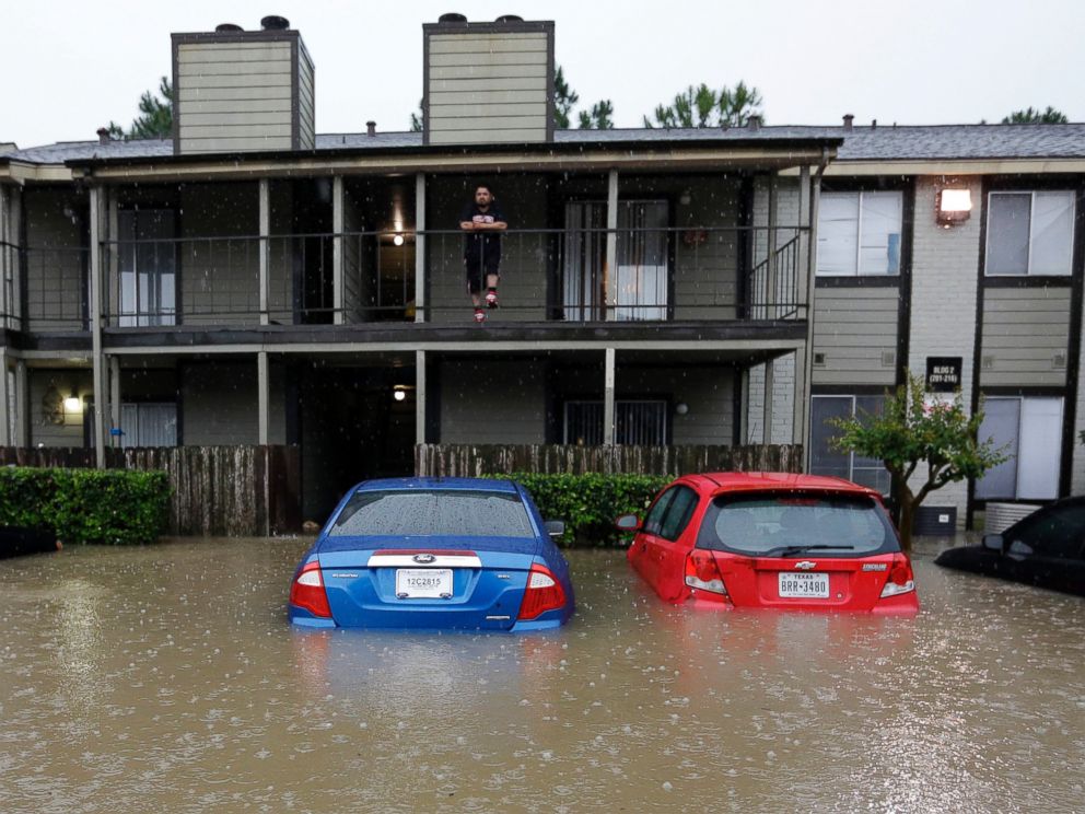 PHOTO: A resident looks out from the second floor as floodwaters surround his apartment complex on April 18, 2016, in Houston.