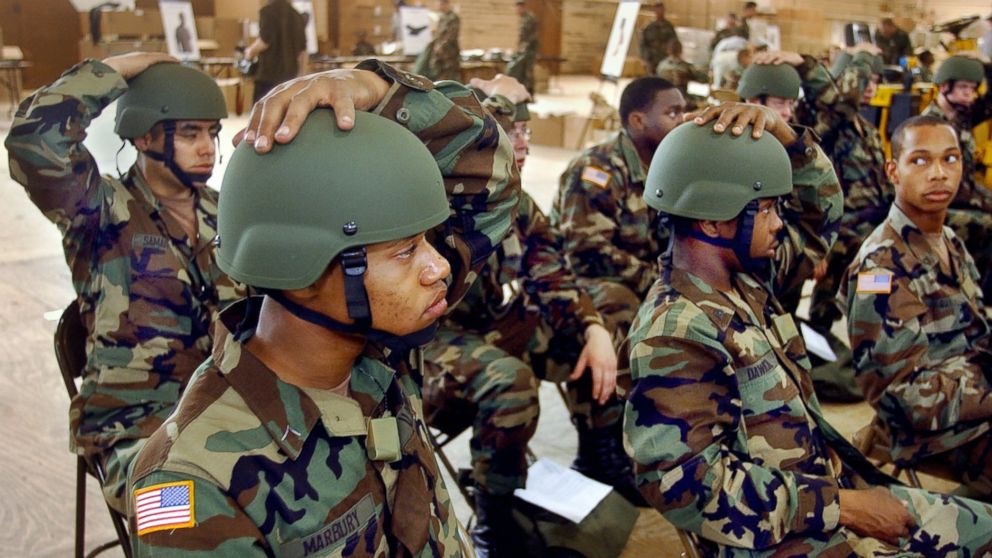 PHOTO: Pvt. Antoine Marbury, C Battery, 2nd Battalion, 15th Field Artillery, and other members of his battery, hold their new advanced combat helmets on their heads during a Rapid Fielding Initiative at Fort Drum, May 13, 2004. 