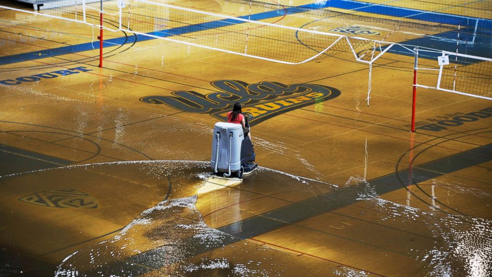 A worker begins the task of cleaning up water covering the playing floor at Pauley Pavilion, home of UCLA basketball, after a water main break, July 29, 2014.