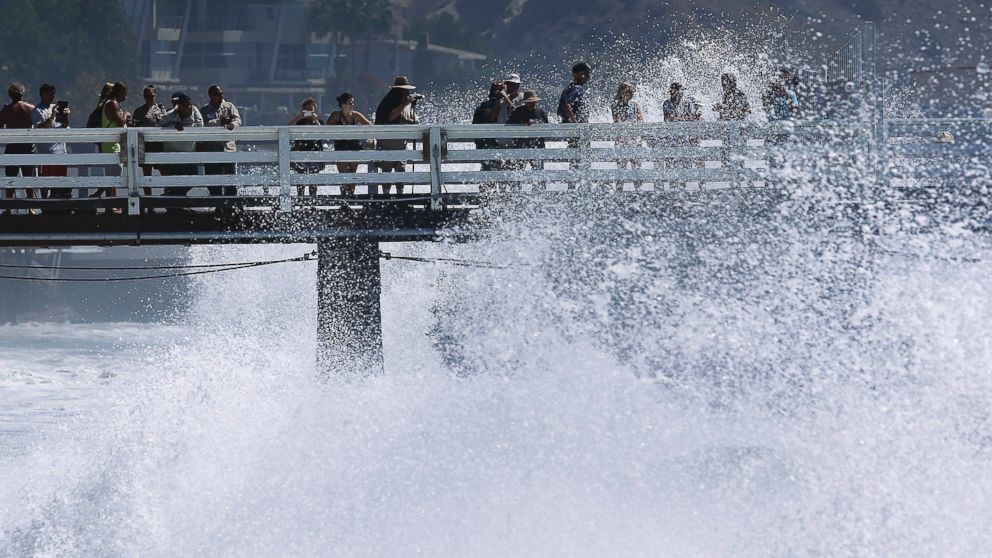 Surf watchers are splashed at the pier in Malibu, Calif., Aug. 27, 2014.
