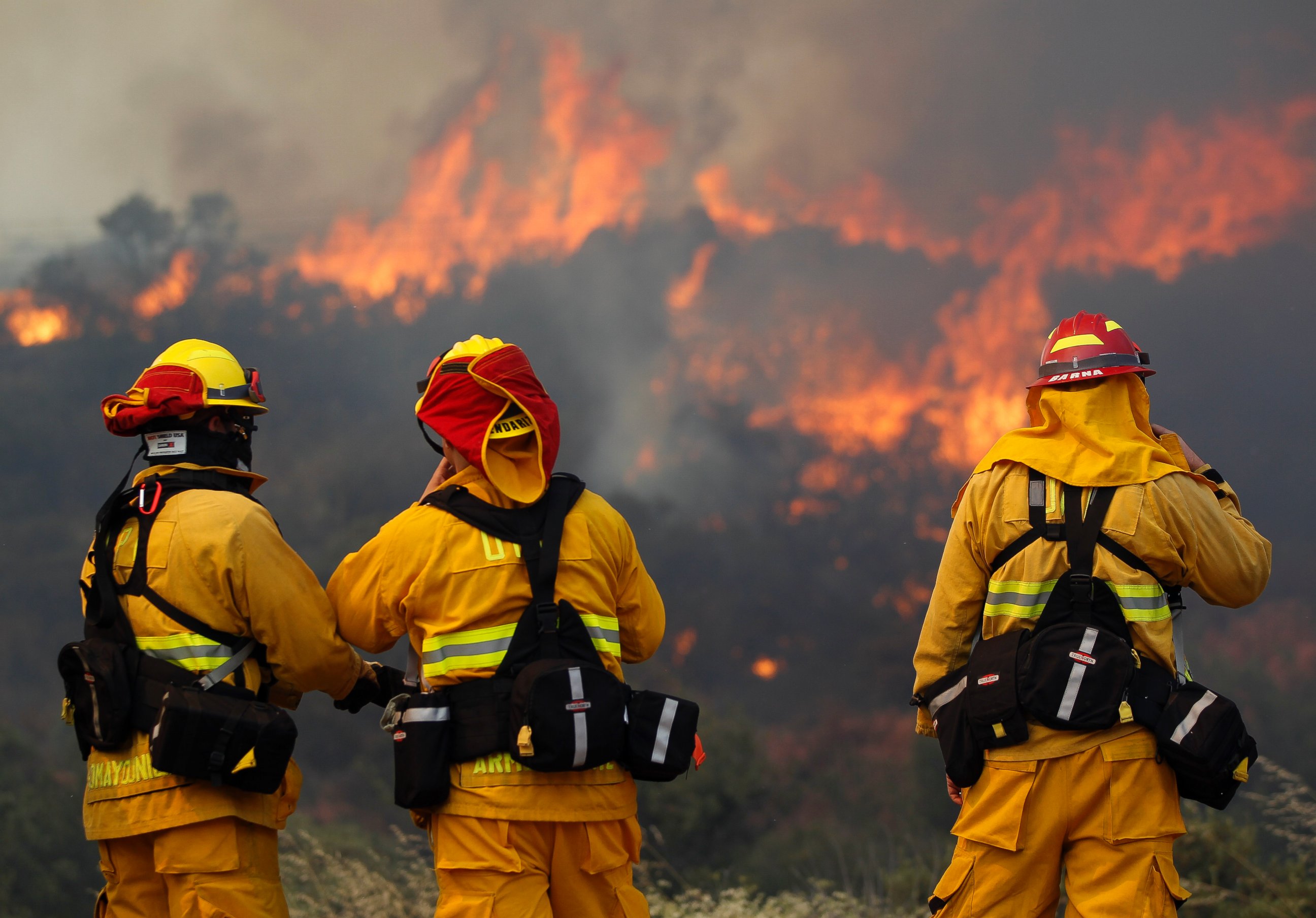 PHOTO: Upland firefighters, from left, Nima Homayounieh, Joseph Armendariz, and Capt. Joe Burna, watch as flames burn toward Highway 94 near Potrero, Calif., June 20, 2016. 