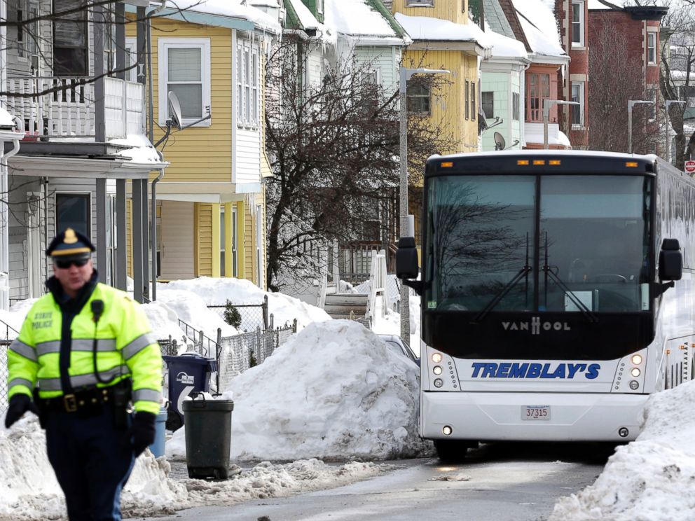 PHOTO: A Massachusetts state police law enforcement official, left, walks near the yellow home, center left, where the late Odin Lloyd lived in Boston, Feb. 6, 2015.