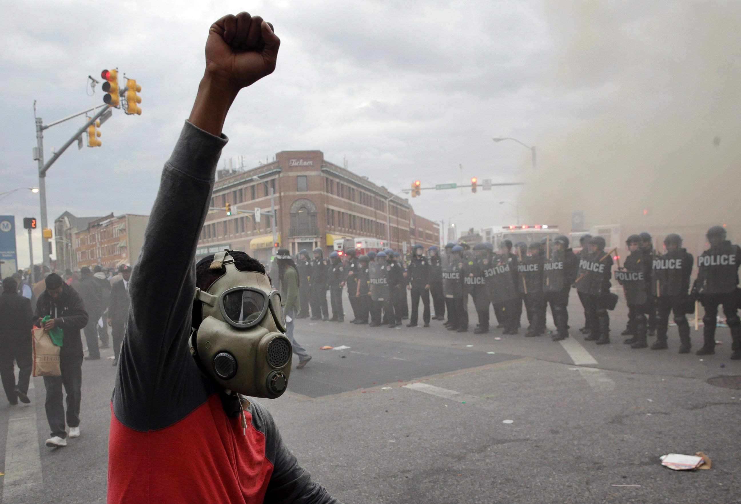 PHOTO: A demonstrator raises his fist as police stand in formation as a store burns, April 27, 2015, in Baltimore.