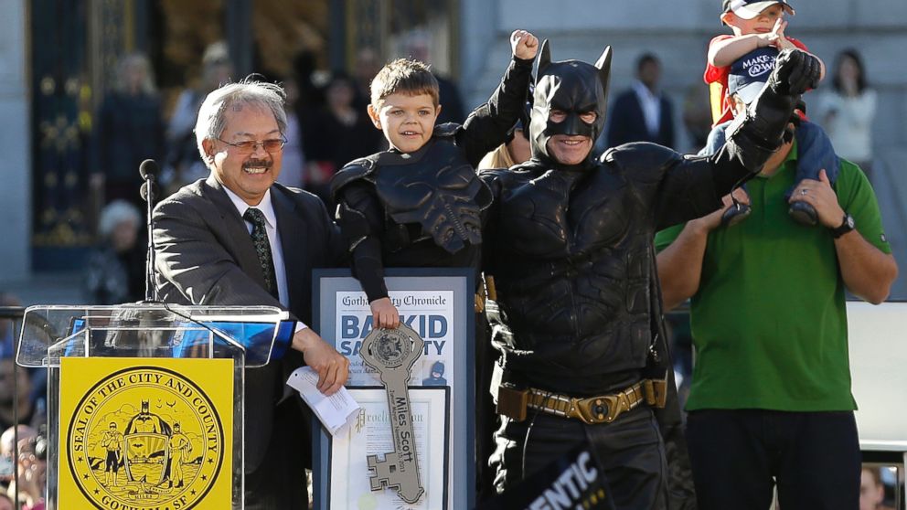 Miles Scott, dressed as Batkid, second from left, raises his arm next to Batman at a rally outside of City Hall with Mayor Ed Lee, left, and his father Nick and brother Clayton, at right, in San Francisco, Nov. 15, 2013.