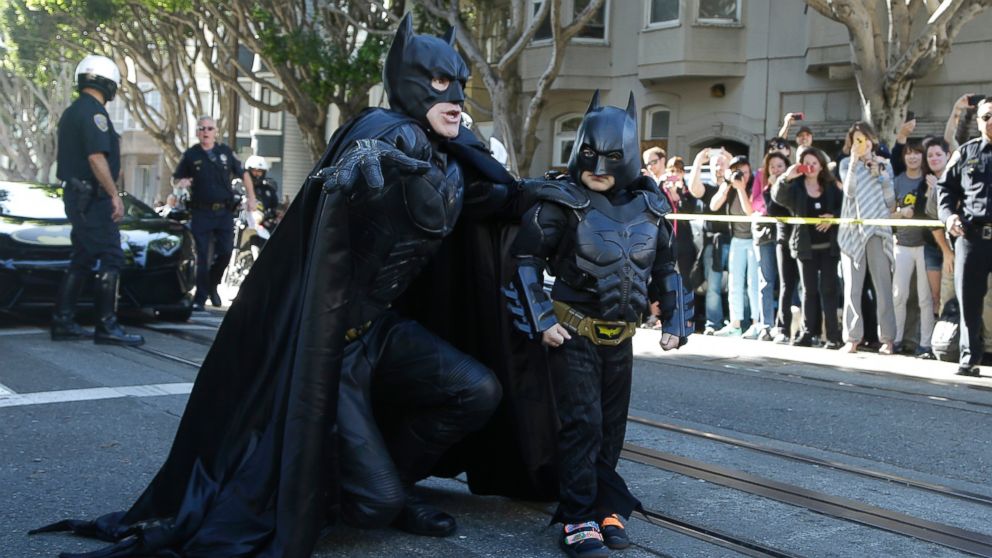 Miles Scott, dressed as Batkid, right, walks with Batman before saving a damsel in distress in San Francisco, Nov. 15, 2013. 