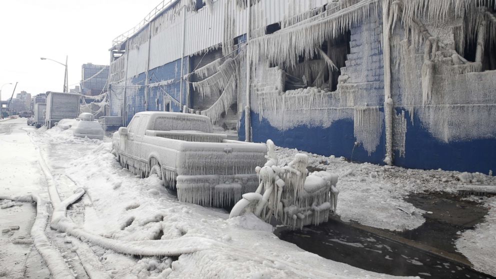 Vehicles and a building are covered with ice as firefighters work to keep a warehouse fire down in the Brooklyn borough of New York, Sunday, Feb. 1, 2015.