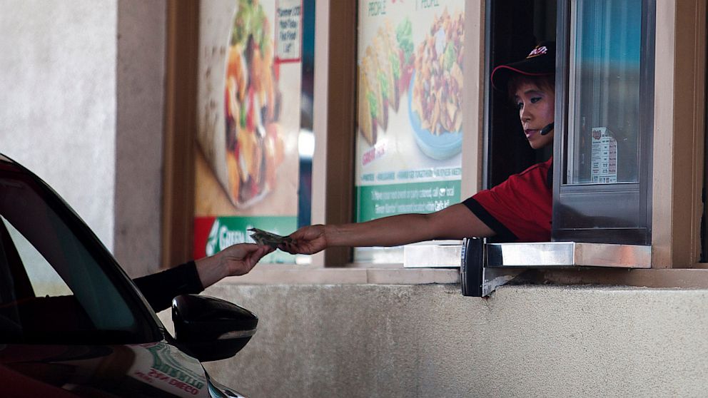 A Carl's Jr. employee gives a customer change through a drive-thru window in San Diego on Friday, Sept. 13, 2013. 