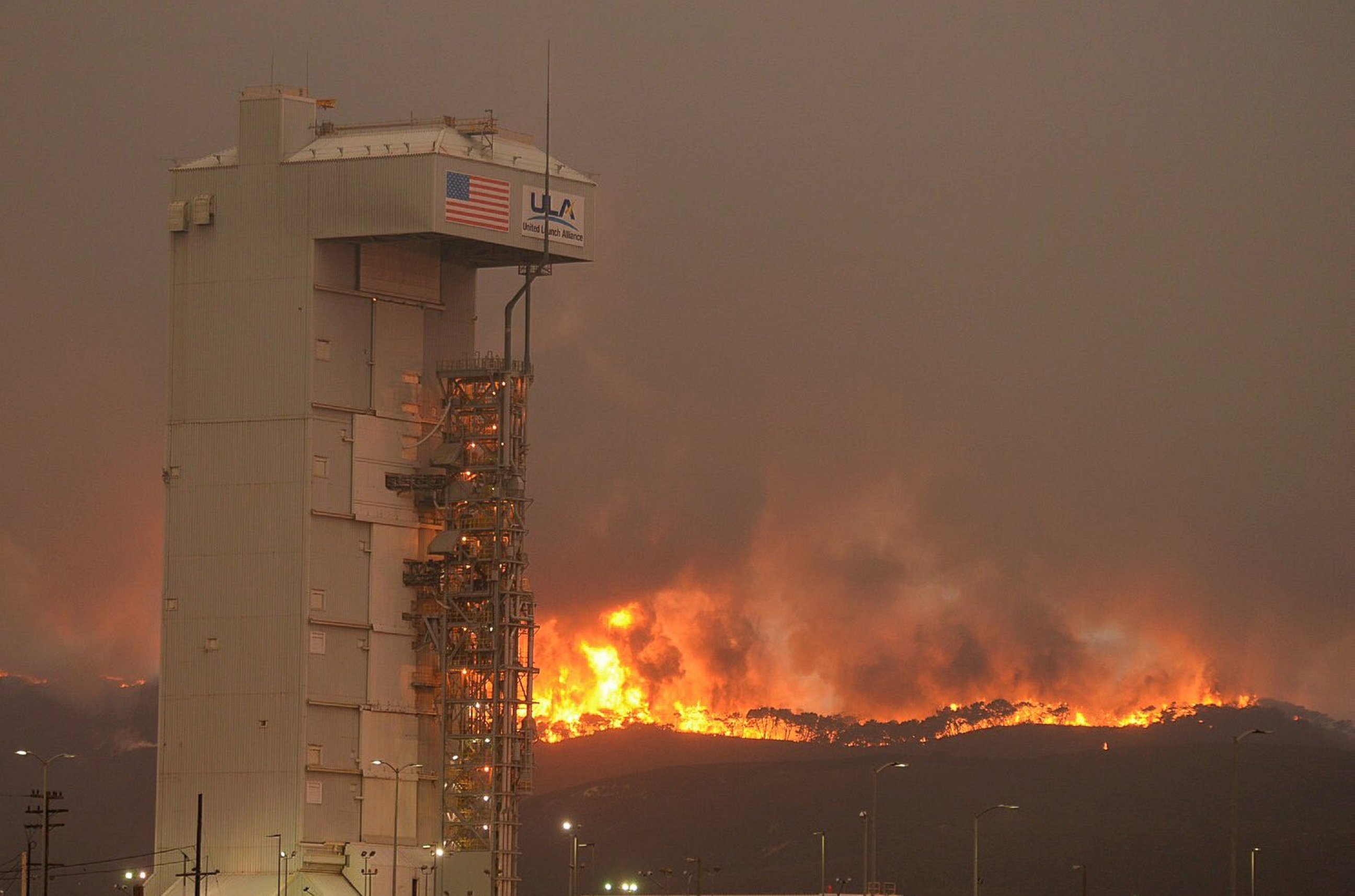 PHOTO: In this Monday, Sept. 19, 2016 photo provided by the Santa Barbara County Fire Department, a fire burns several miles behind Space Launch Complex-3, housing the Atlas V rocket & WorldView 4 satellite, at Vandenberg Air Force Base, California. 