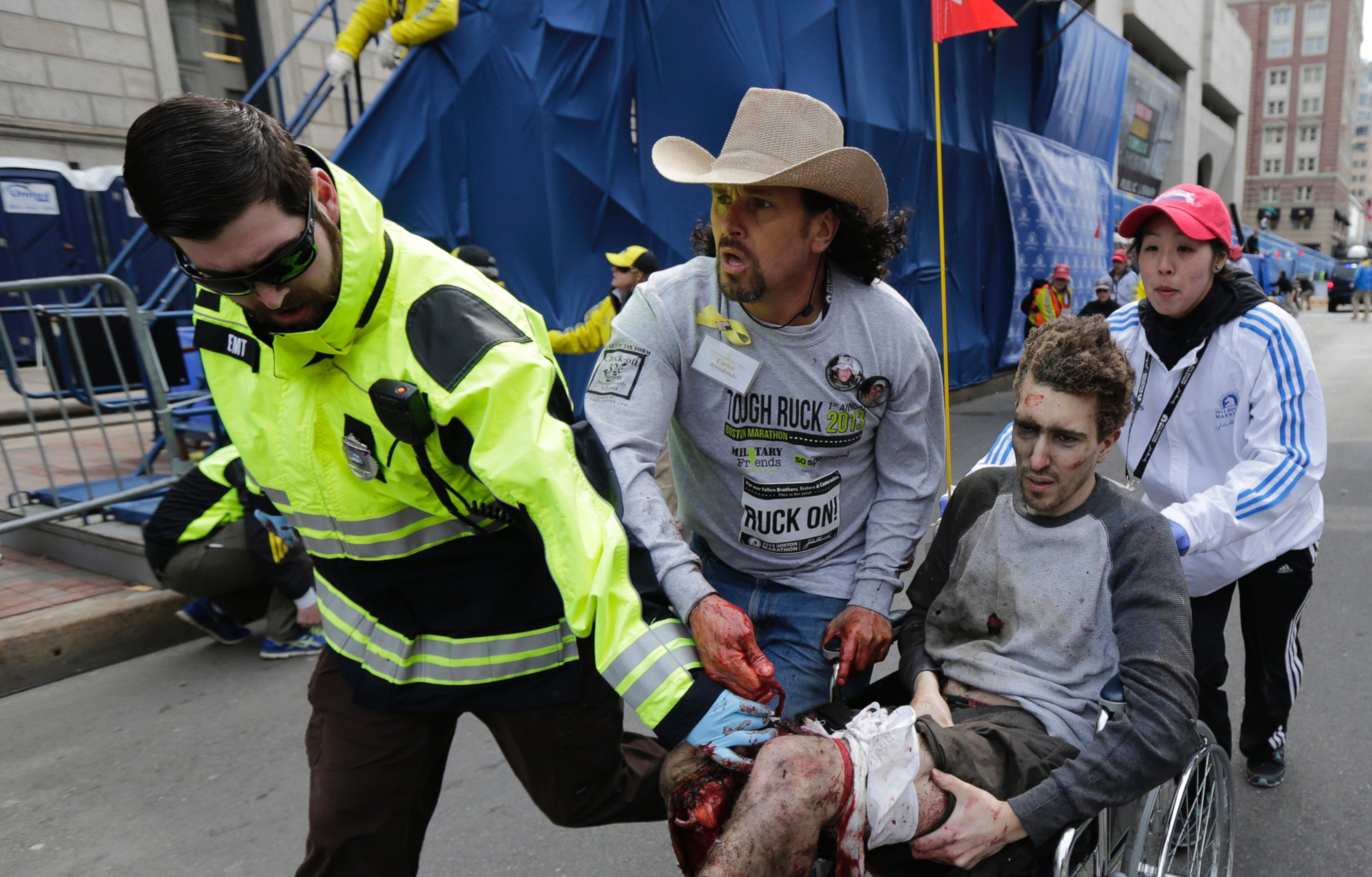 PHOTO: An emergency responder and volunteers, including Carlos Arredondo in the cowboy hat, push Jeff Bauman in a wheel chair after he was injured in an explosion near the finish line of the Boston Marathon Monday, April 15, 2013 in Boston.