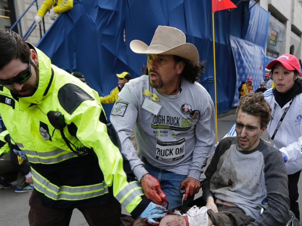 PHOTO: An emergency responder and volunteers, including Carlos Arredondo in the cowboy hat, push Jeff Bauman in a wheel chair after he was injured in an explosion near the finish line of the Boston Marathon Monday, April 15, 2013 in Boston.