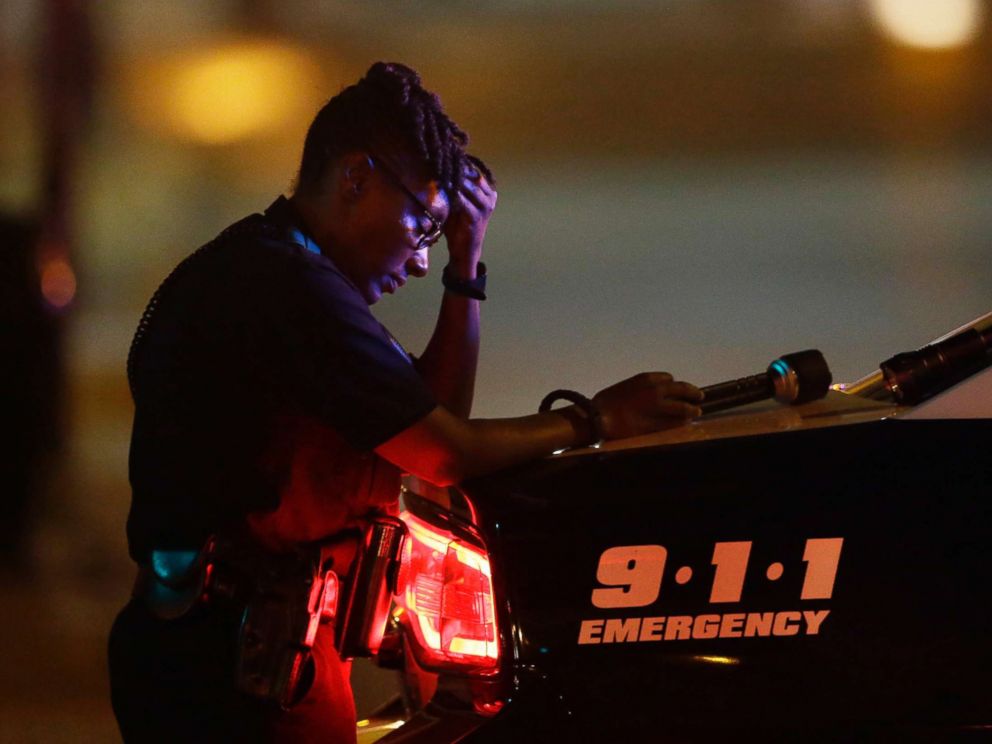 PHOTO: A Dallas police officer, takes a moment as she guards an intersection after a shooting in downtown Dallas, July 8, 2016.