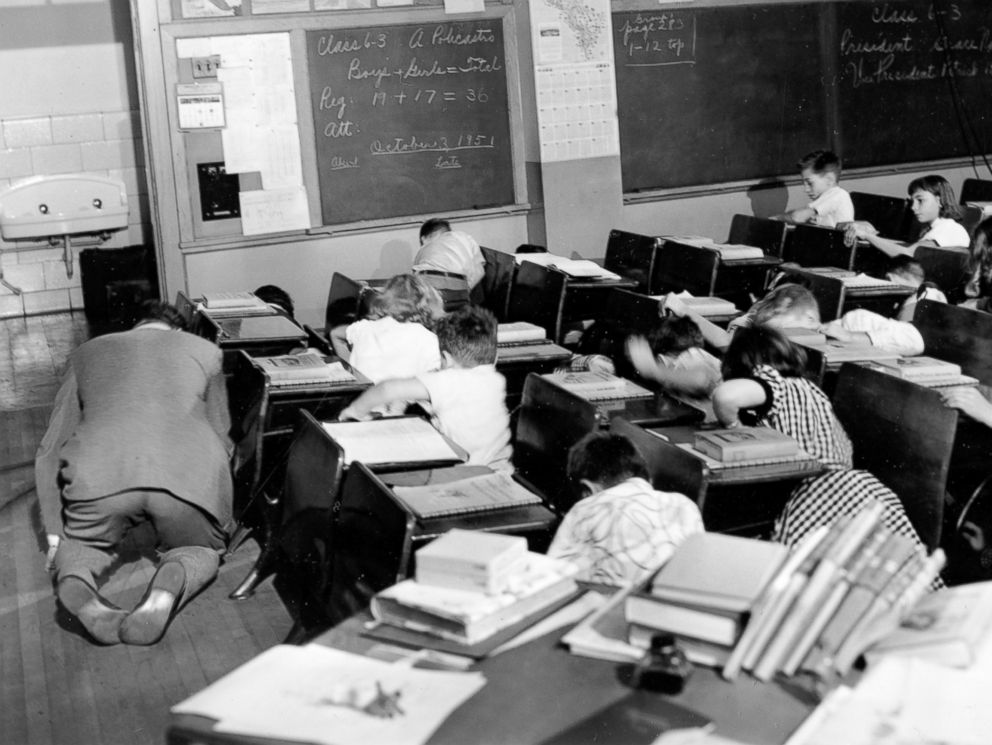 PHOTO: Sixth grade students crouch under or beside their desks along with their teacher as they act out a scene from the Federal Civil Defense administration film "Duck and Cover" in the Queens, Nov. 21, 1951.